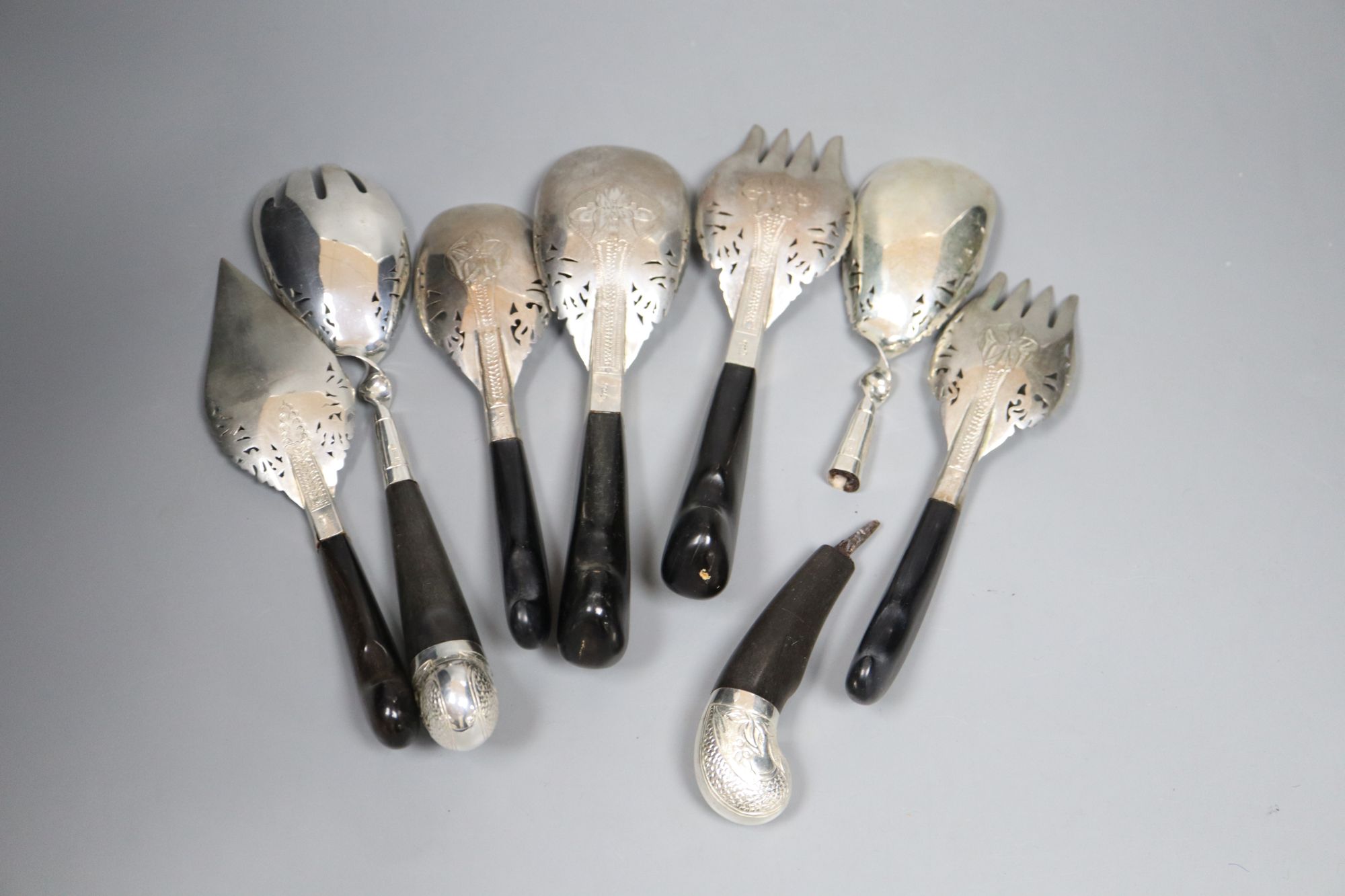 A group of assorted Thai ebony handled engraved white metal servers, one a.f.